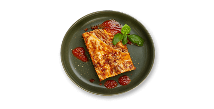 Rebanada de lasaña con salsa de tomate y albahaca en un plato verde oscuro.